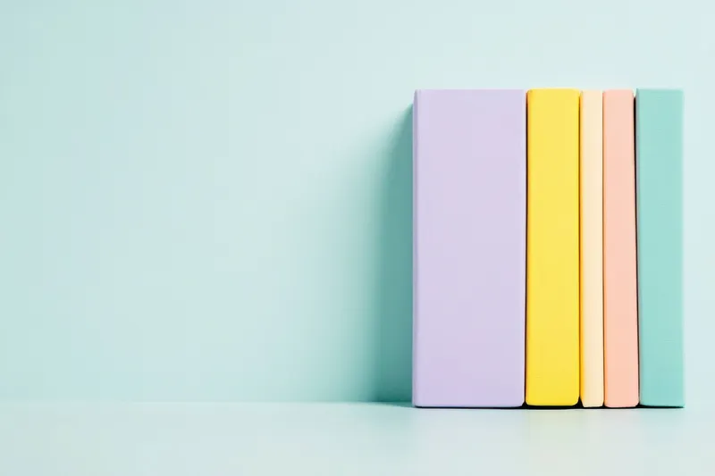 Эстетичная композиция из красочных книг в пастельных оттенках на фоне мяты, идеально подходящая для продвижения идей образования, творчества и знаний