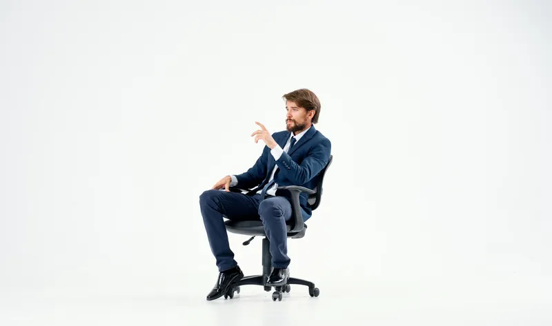 Бизнесмен сидит в офисном кресле и работает на изолированном фоне
