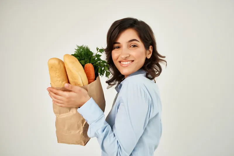 Брюнетка с пакетом полезных продуктов делает покупки в супермаркете