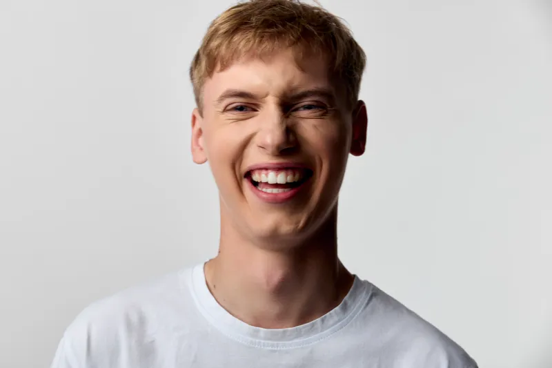 Smiling man in a white tshirt radiates happiness and cheerful energy, ideal for lifestyle and advertising campaigns with a bright, positive mood and friendly appeal