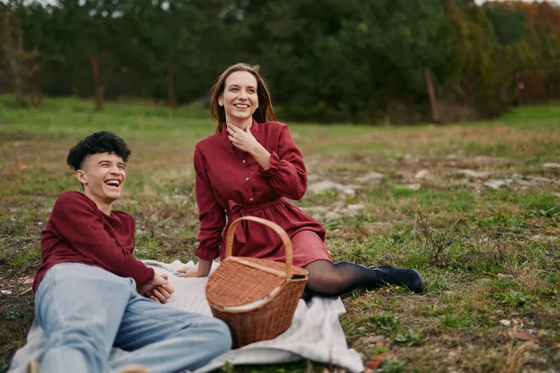 Candid outdoor picnic portrait of a smiling couple sharing a genuine connection on a blanket, natural expressions and simple styling capturing believable, relatable daily moments.