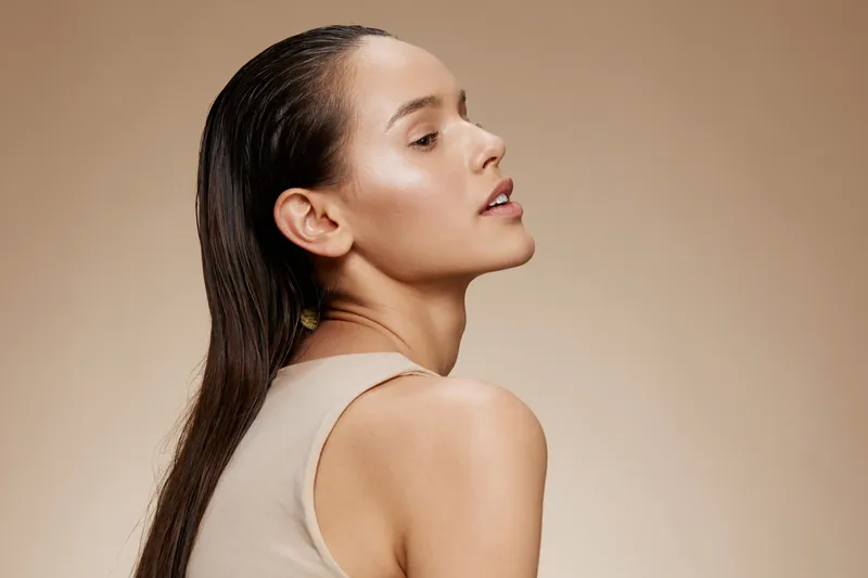 Elegant female model with wet hair showcasing natural beauty, minimal makeup, and a neutral background for beauty and skincare concepts