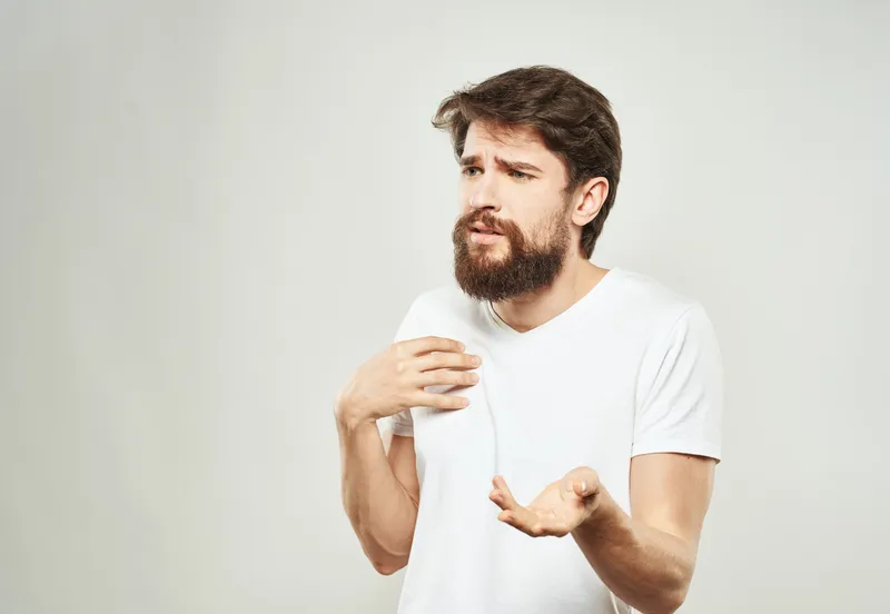 Мужчина в белой футболке на светлом фоне, модель с эмоциями, жестикулирующая руками