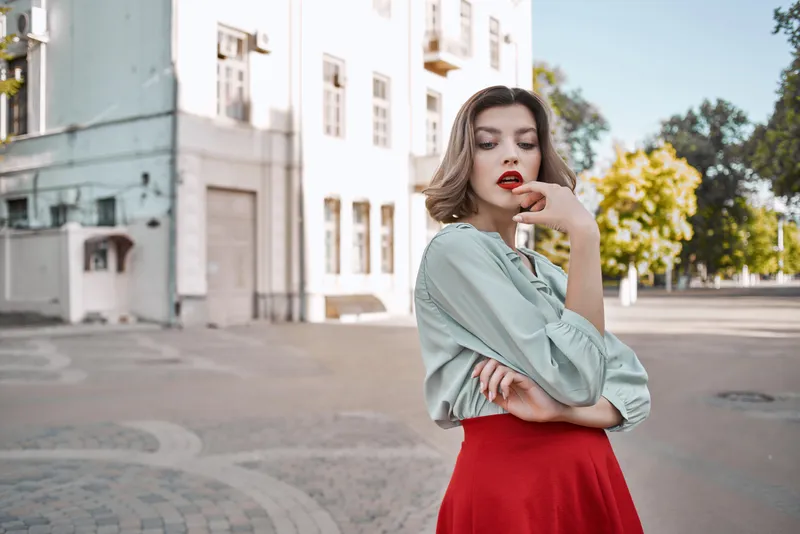 Милая блондинка в красной юбке на улице, на площади, идет