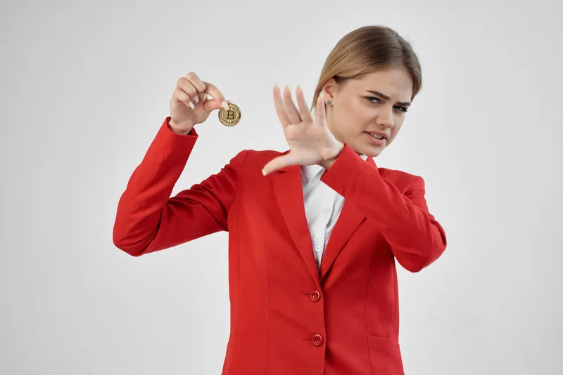 Женщина в красной куртке держит золотую монету Bitcoin на изолированном фоне