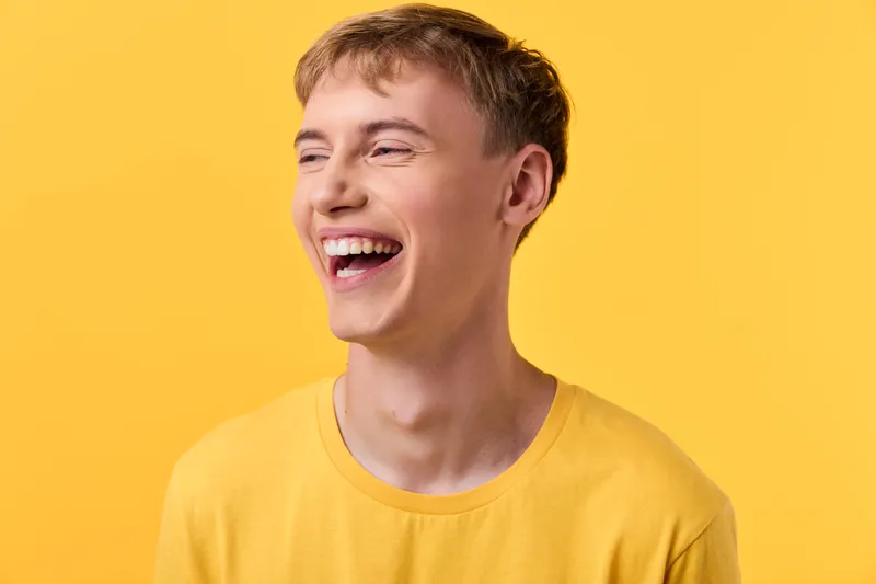 Smiling man wearing a yellow shirt against a bright yellow background, radiating happiness, energy and cheerful vibe in a clean studio setting with vivid color and positive mood