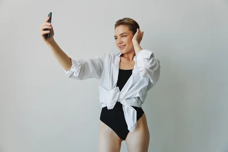 Девушка-подросток, блогер, фотографирует и снимает себя на видео на телефон для контента в социальных сетях