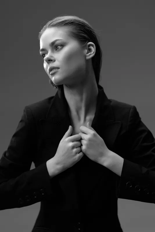 Black and white portrait of a thoughtful woman wearing a blazer with a serious expression.