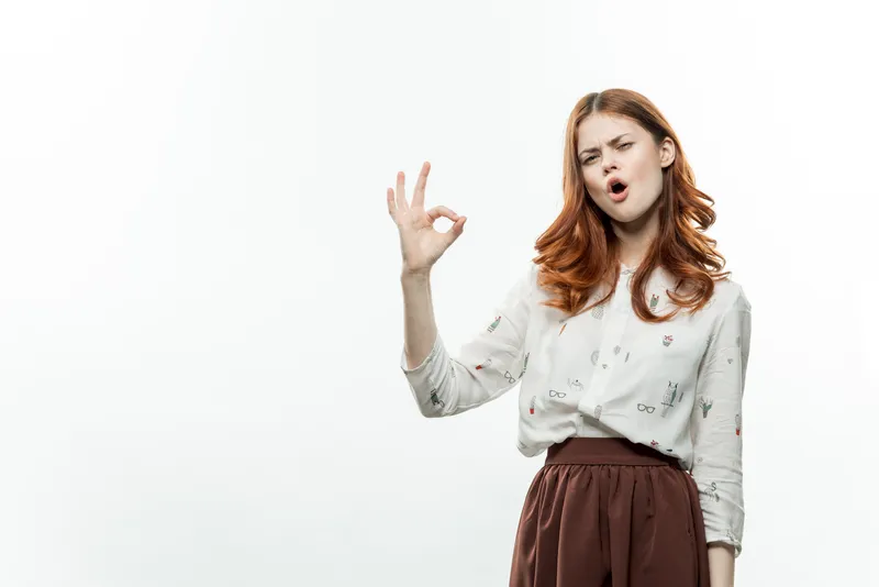 Красивая женщина с рыжими волосами в деловом костюме жестикулирует руками в студии