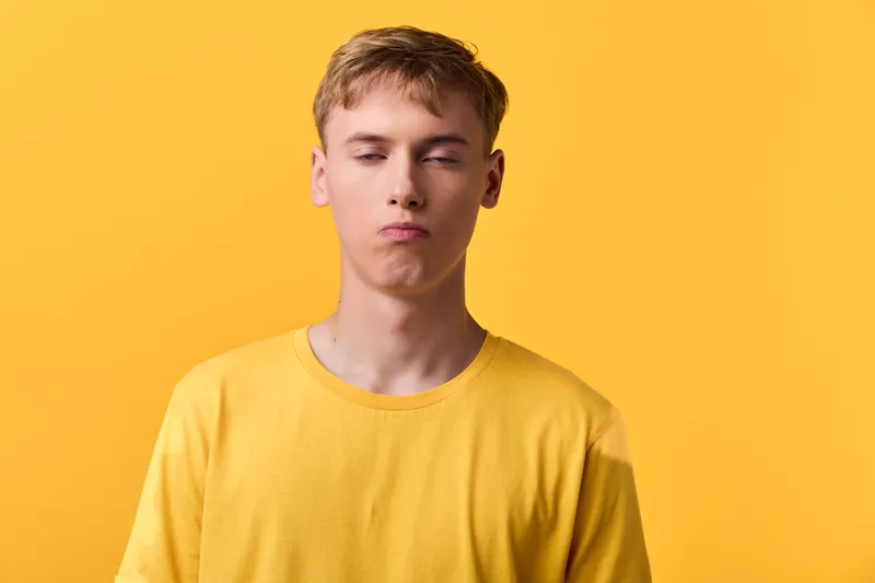 Pouty expression on a man wearing a yellow shirt against a bright background, studio shot with bold color and casual fashion mood, playful vibe for lifestyle and stock use in creative projects