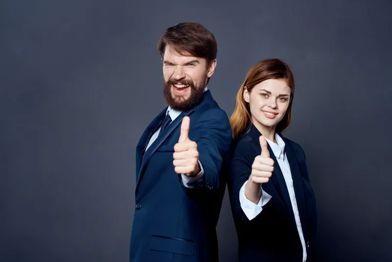 Весёлые мужчина и женщина, коллеги по работе, в команде на тёмном фоне