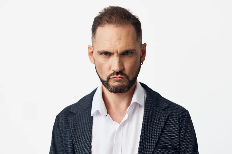 Professional businessman portrait with a focused expression, isolated on a colored background, conveying confidence, determination, and a calm, intense mood suitable for corporate communication.