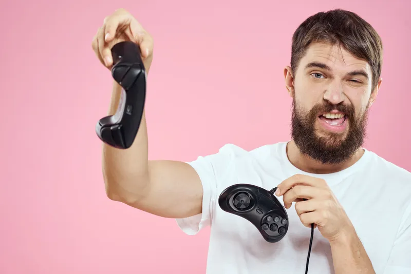 Мужчина с двумя джойстиками в руках, веселая игра, технологии, образ жизни, розовый фон