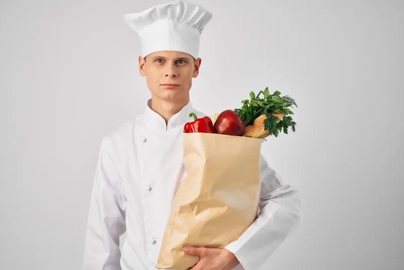 Шеф-повар с упаковкой свежих продуктов занимается доставкой из ресторана