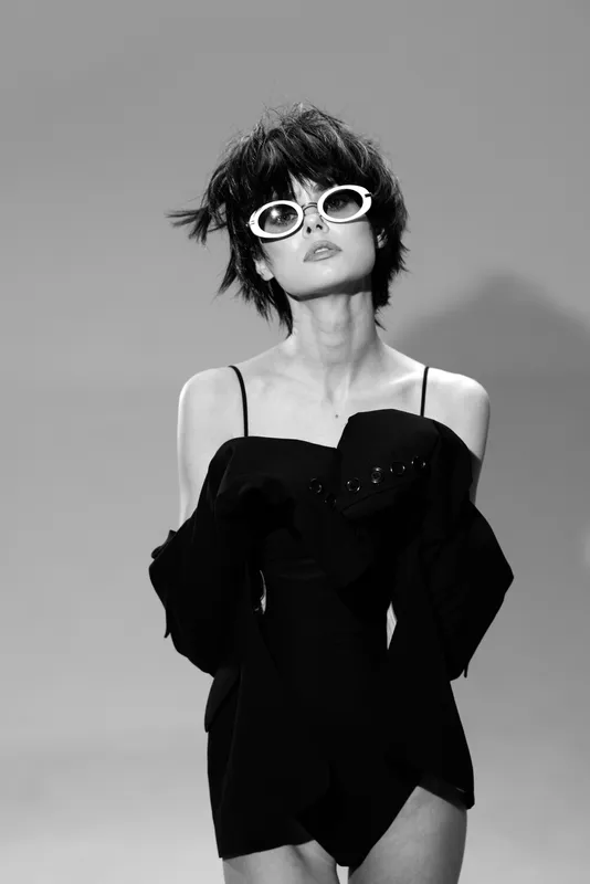 stylish woman in black dress and sunglasses with short hair in black and white fashion portrait