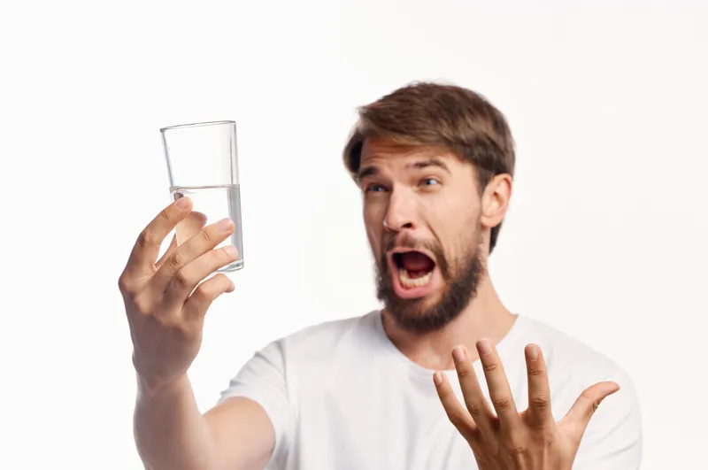 Бородатый мужчина со стаканом воды в студии