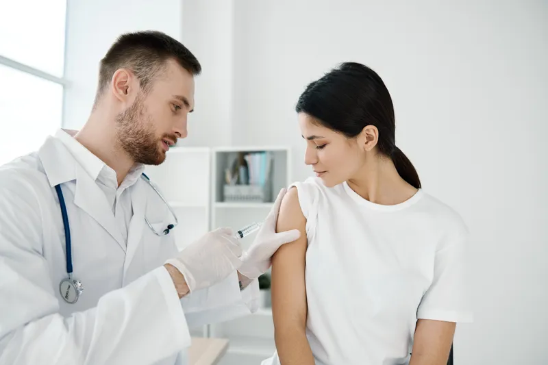 Женщина в больнице, и врач делает ей инъекцию вакцины от коронавируса