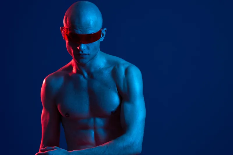muscular man with futuristic sunglasses, glowing blue skin, and dramatic lighting creates a striking visual composition in this captivating image.
