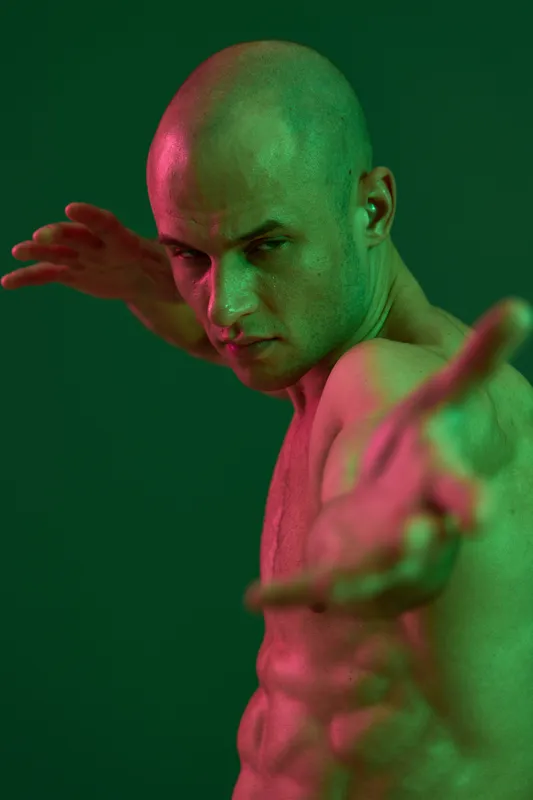Strong man posing with an intense expression, showcasing defined muscles under dramatic lighting, creating a bold and dynamic visual impact.