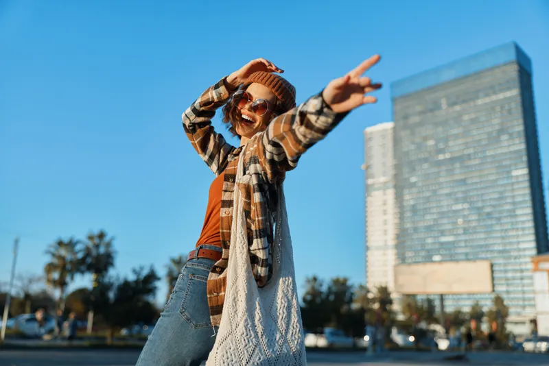 Woman joy urban fashion candid golden authenticity lifestyle captured in a warm golden hour glow, smiling carefree on city street with boho outfit and emotional storytelling mood.