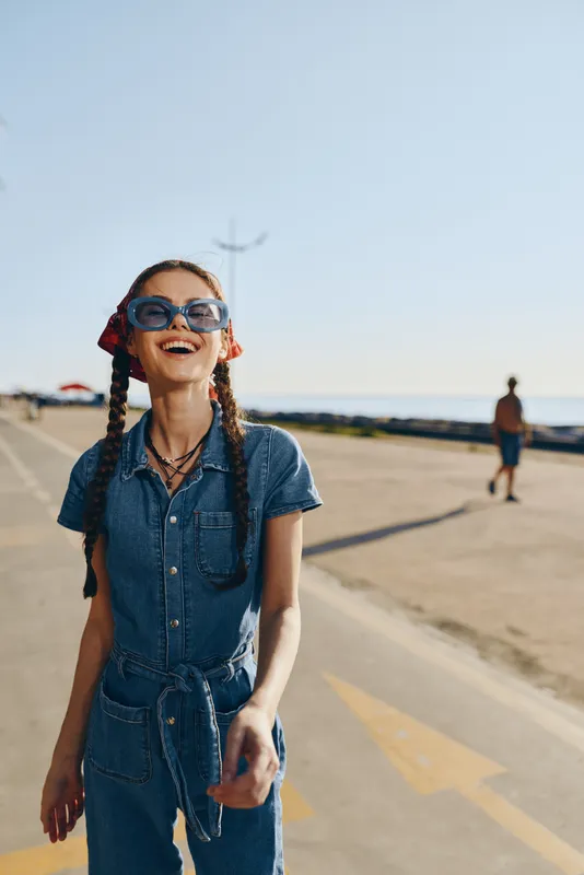 lifestyle woman in modern boho-western denim street style smiling brightly outdoors with film color effect, casual outfit, summer day, joyful mood