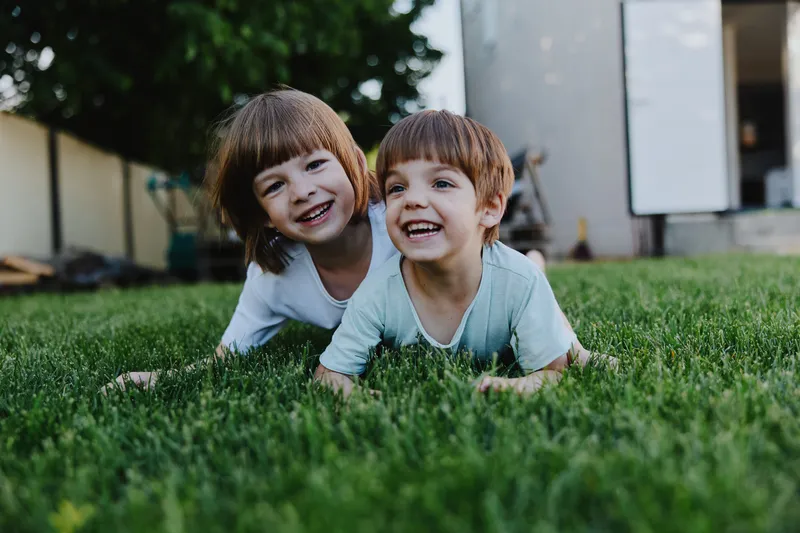 Happy children playing together on green grass, enjoying a sunny day with smiles and laughter. Perfect for summer activities and family moments.