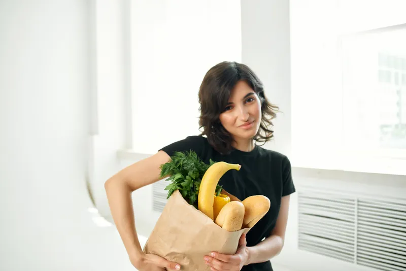Женщина в чёрной футболке с пакетом продуктов, покупки, домашние дела