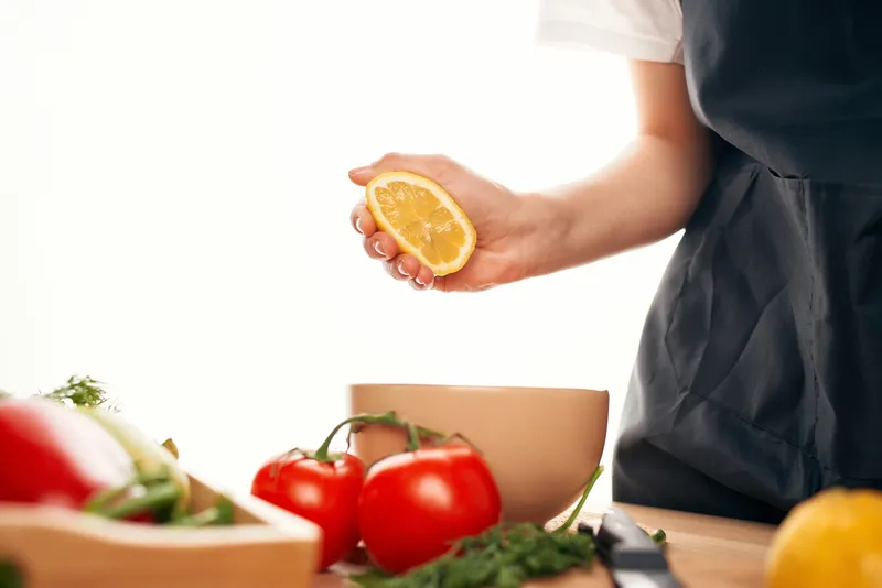Лимон в руке, кухня, нарезка овощей для салата, приготовление еды
