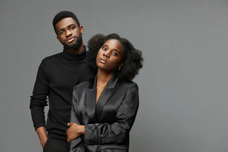 Two stylish young adults with confident expressions pose in modern fashion, embodying sleek aesthetics, showcasing diversity and contemporary elegance