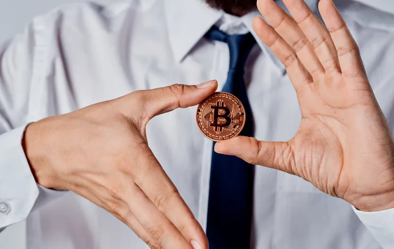 Монета Биткоин в руках бизнесмена, который успешно управляет криптовалютой