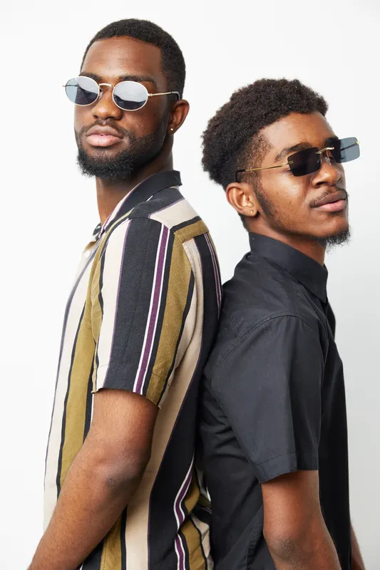 Two stylish black men posing back to back, wearing sunglasses and fashionable attire, exuding confidence and modern style. Perfect for fashion and lifestyle themes.