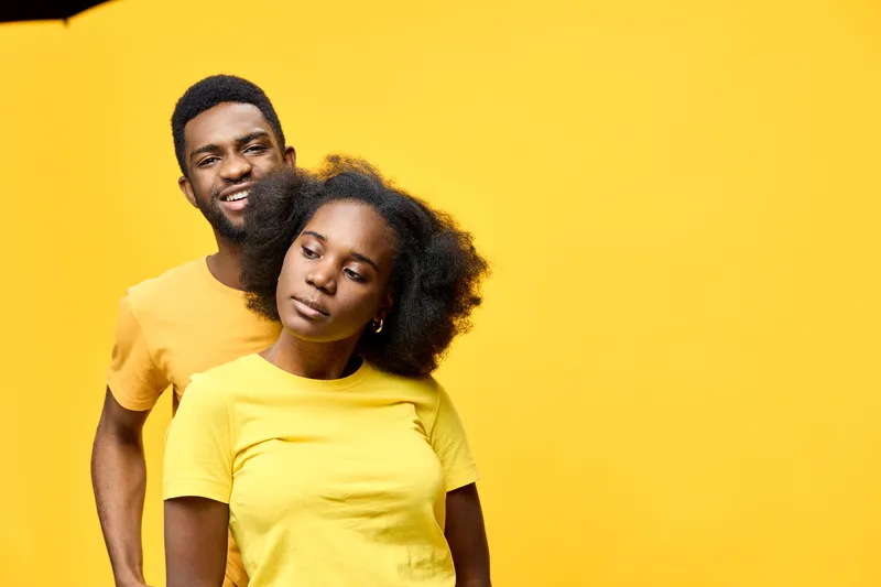 Happy young couple with vibrant yellow clothing against a bright yellow background, showcasing joy and connection in a cheerful setting