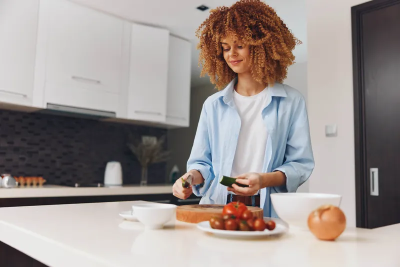 Афроамериканка готовит вкусное блюдо на своей домашней кухне, основное внимание уделяется процессу приготовления и ингредиентам