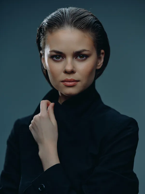 Serious woman with wet hair wearing dark clothing with intense gaze and moody lighting