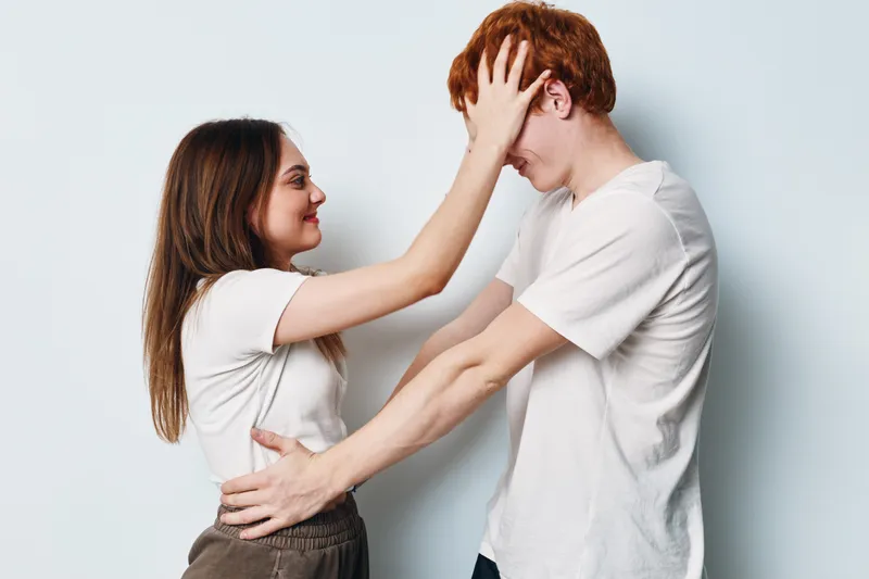Young couple smiling and playfully touching each other on white background with casual clothes for relationship and affection, love and happiness.