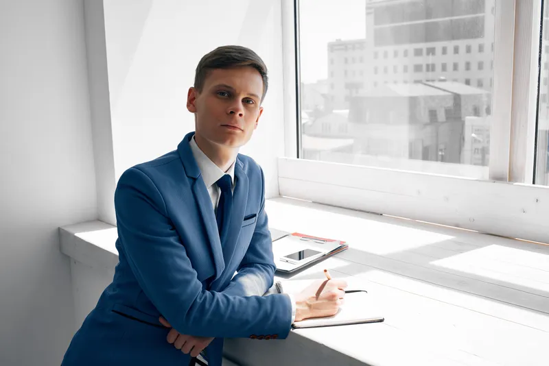 Бизнесмен-менеджер работает с документами в офисе у окна