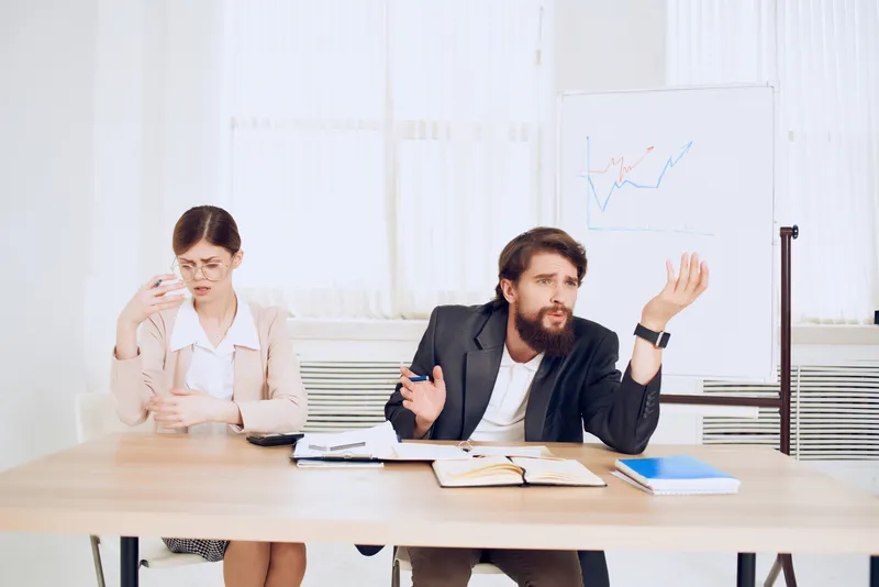 Эмоциональный мужчина и женщина на работе, коллеги в процессе рабочего общения
