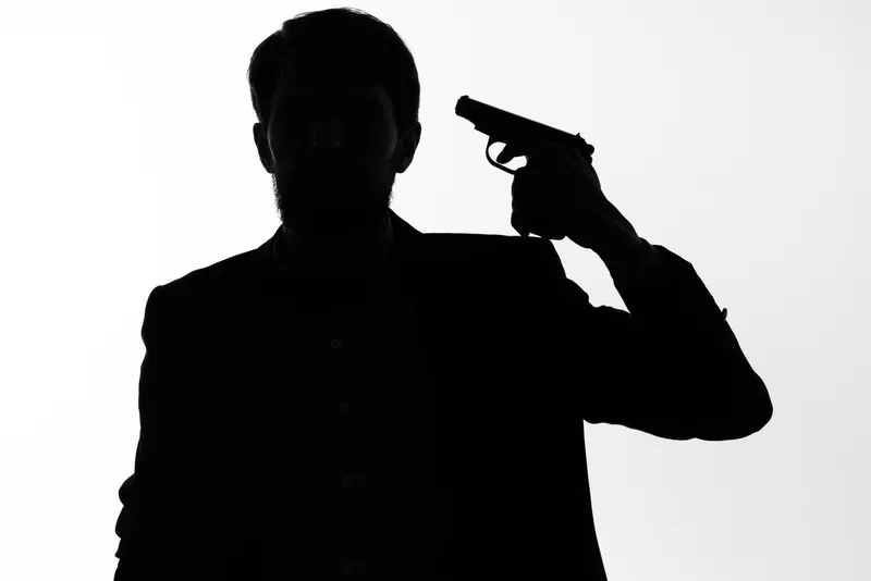 Тень мужчины с пистолетом в руках, целящегося; суицид, опасность