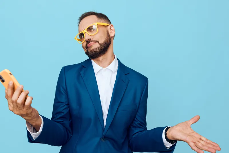 A professional man in a blue suit exudes confident curiosity against a solid colored background, capturing a modern business vibe and subtle emotion of intrigue.