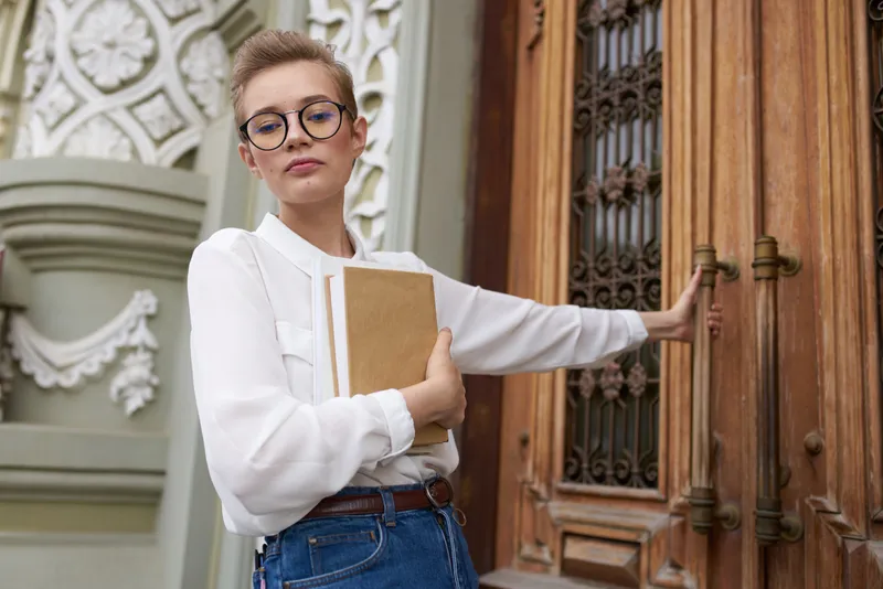 Студент с книгой в руках на открытом воздухе, читает