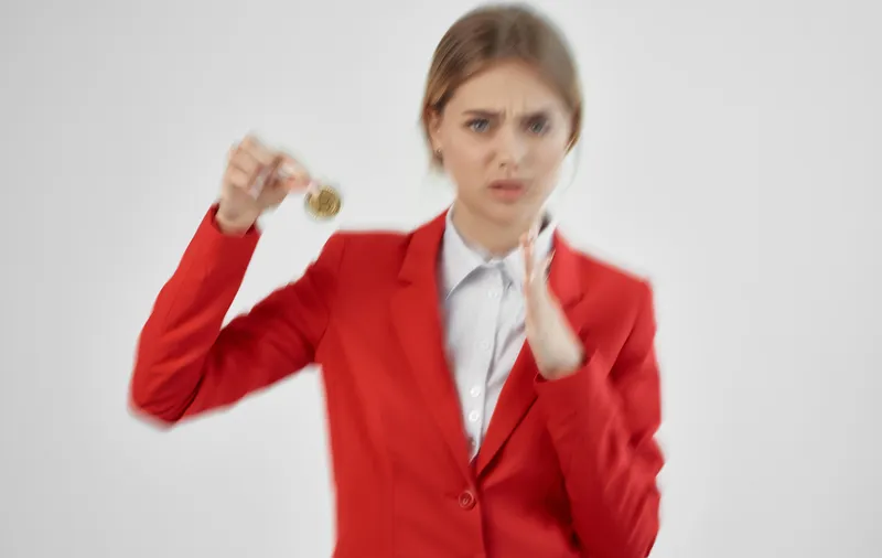 Женщина в красном пиджаке держит в руках криптовалюту Bitcoin, что символизирует электронную коммерцию и финансы