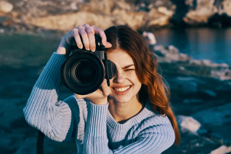 Женщина с фотоаппаратом на природе, снимающая пейзаж