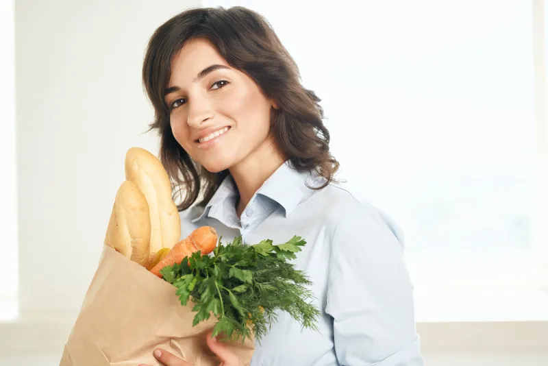 Женщина с пакетом продуктов, овощей в супермаркете, совершает покупки