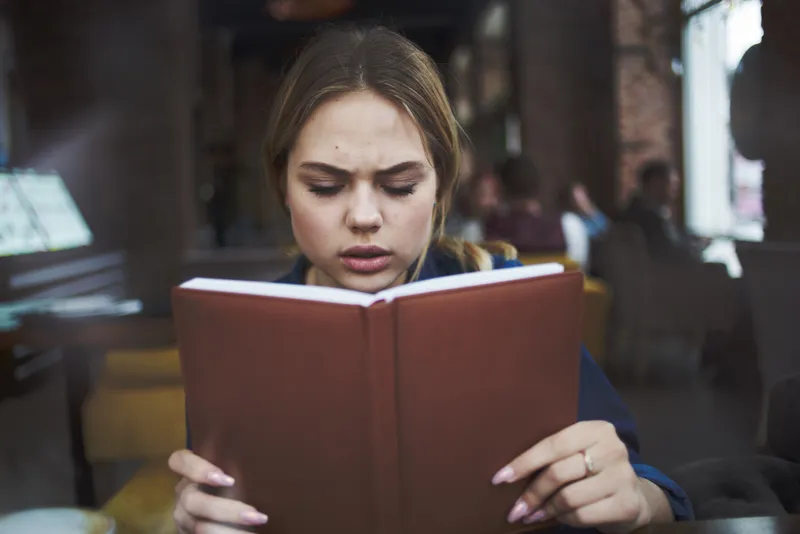 Деловая женщина с книгой в руках и чашкой кофе в кафе, ведущая активный образ жизни