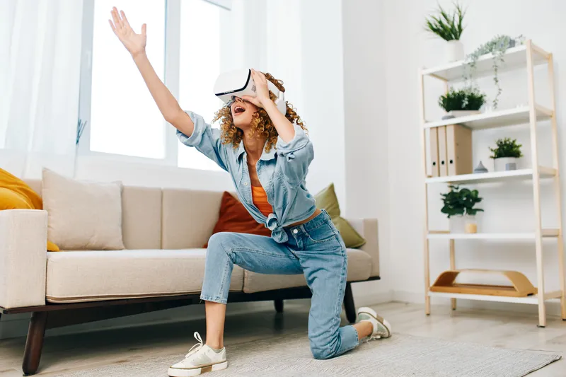 Виртуальная реальность: улыбающаяся женщина в футуристических VR-очках наслаждается игрой дома