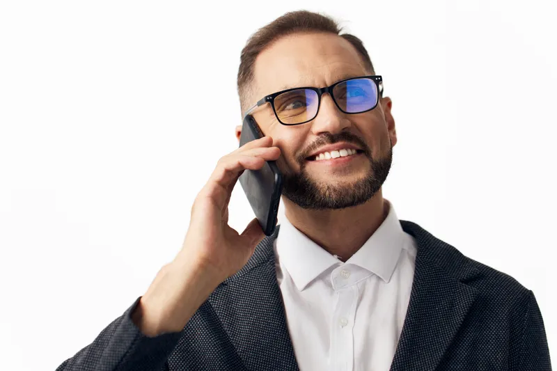 A confident business professional talks on a smartphone, smiling with warmth against a vivid isolated color background, conveying success, focus, and approachable energy.