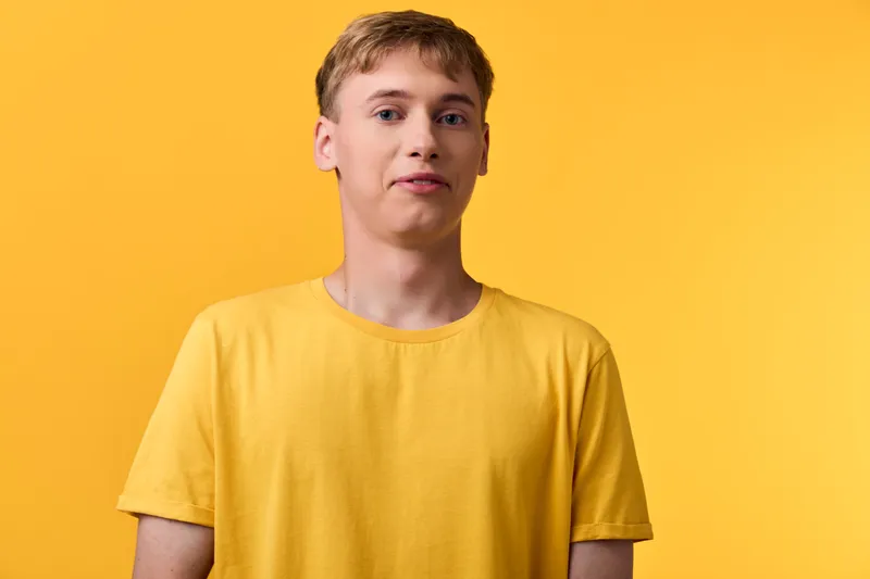 Young man in a yellow t shirt against a solid yellow background, casual fashion and bright studio lighting, clean composition, upbeat color mood and simple modern style.