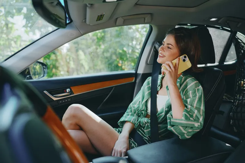 Car, woman, smile, a cheerful woman sits inside the car, wearing a green striped shirt, talking on a mobile phone, relaxed and confident, inviting readiness for a journey and future adventures