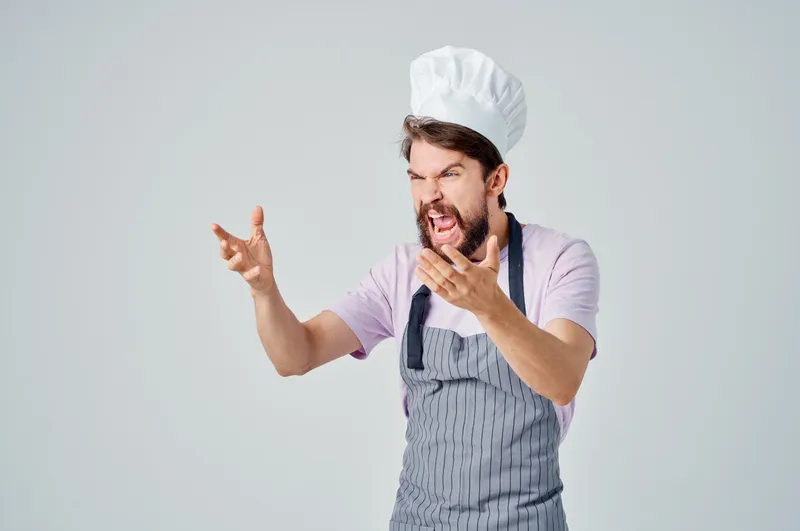 Мужчина в фартуках занимается профессиональной работой по приготовлению пищи