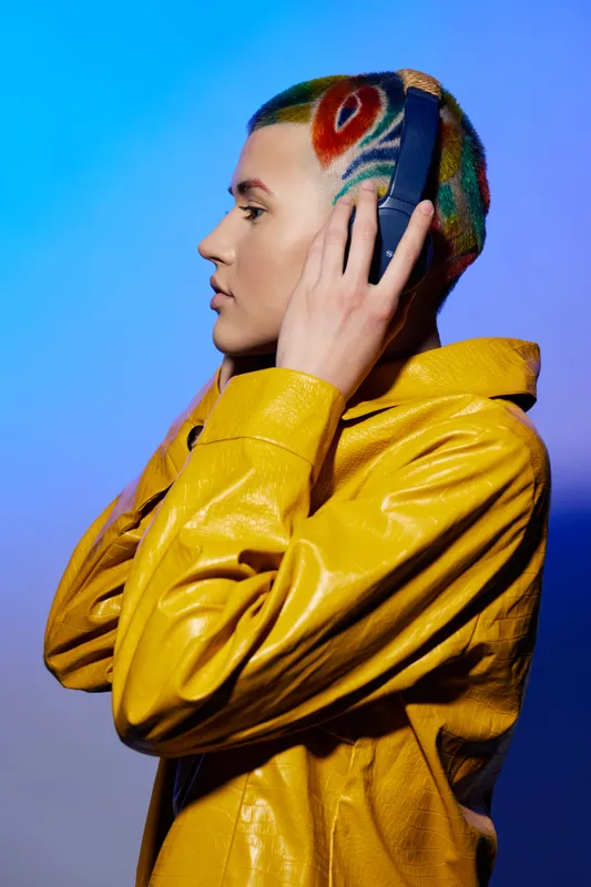 young woman with colorful hairstyle wearing yellow jacket and headphones, listening to music, vibrant and modern style, studio lighting background